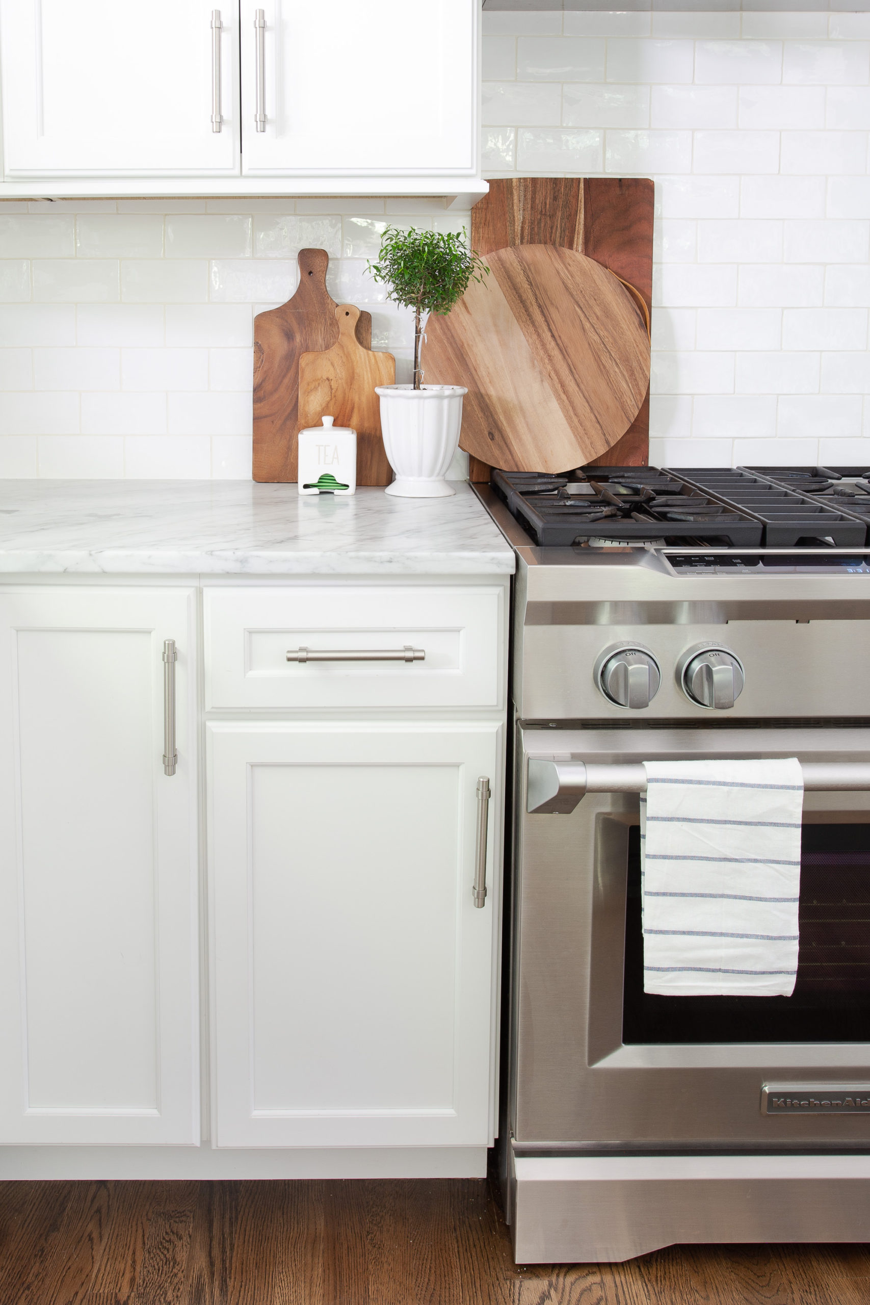 Gas range in white kitchen with towel and wooden trays